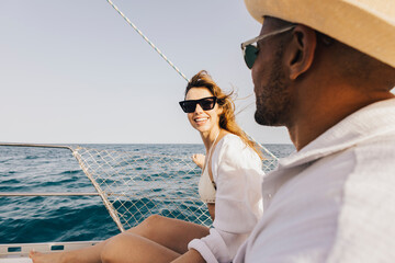 A cheerful couple relaxes on a sailboat under sunny skies, embracing the freedom and joy of the open sea. Perfect summer adventure mood.