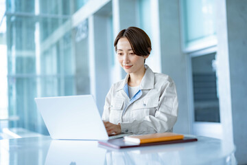 パソコン作業をする作業着を着た女性