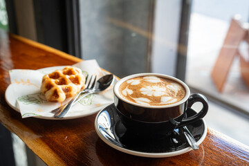 Hot coffee latte with latte art milk foam in cup mug and Homemade Belgian Waffles with honey on wood desk on top view. As breakfast In a coffee shop at the cafe,during business work.