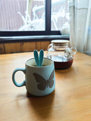 A cup with the ears of a toy rabbit sticking out of it. It's winter outside. The concept of the imminent onset of spring