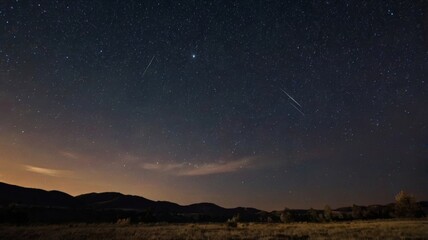Shooting stars crossing a starry night sky over a mountain range