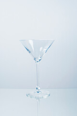 Clear minimal martini cocktail glass on a mirror table with reflection