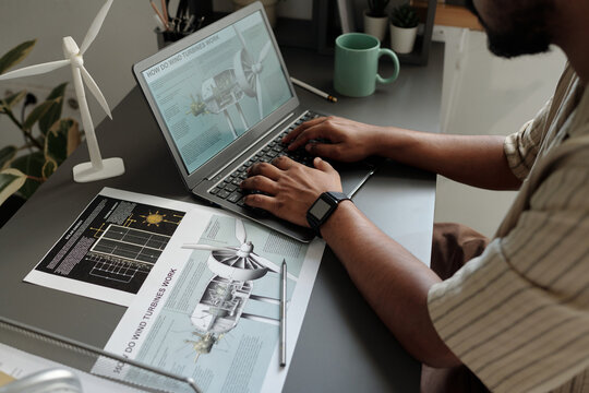 Hands of male engineer typing on keyboard of laptop while working with online document by workplace