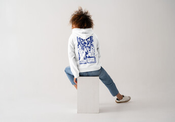 Mockup Of Woman Sitting On Plinth Wearing Customized Hoodie