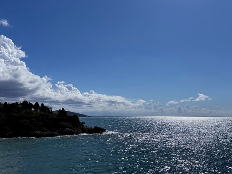 Sea shiny water, blue sky, amazing clouds and rocky coast scenic landscape 