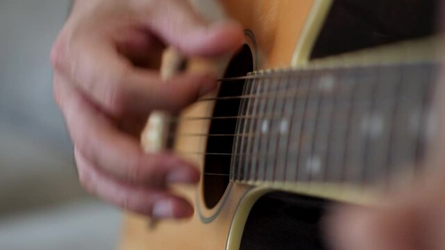 A close-up shot of a hand strumming the strings of an acoustic guitar at home, capturing the beauty and simplicity of making music.