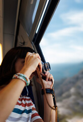 train travel. A young woman enjoys a train ride and takes pictures of beautiful tourist spots with her camera.  the girl uses a film camera.