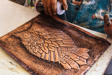 Varnishing aged copper sheet with engraved owl design