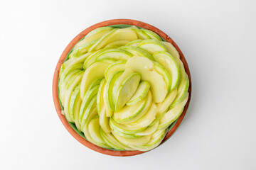 Top view of a ceramic bowl filled with thinly sliced green apples, ideal for healthy eating and diet concepts