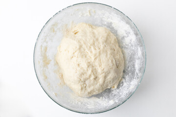 Close-up of freshly kneaded pizza dough in a glass bowl for Italian cuisine preparation on World Pizza Day