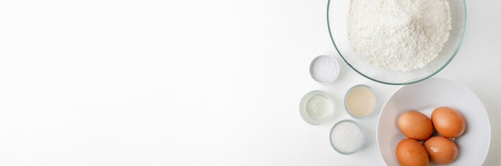Ingredients for baking, including flour, eggs, and sugar, arranged neatly on a white background, perfect for holiday baking preparations