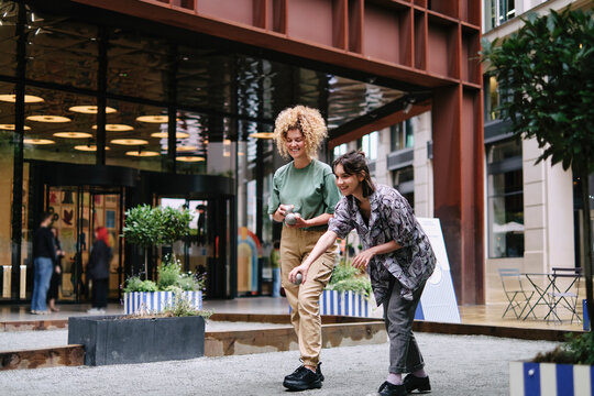 Happy lesbian couple playing boccia balls in fornt of building