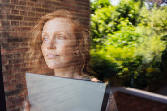 Thoughtful freelancer looking out of glass window