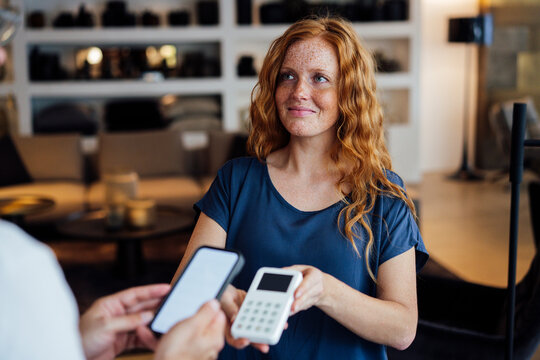 Smiling saleswoman giving credit card reader to customer at store