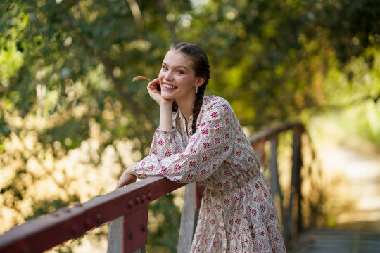 Happy beautiful woman standing in front of trees on bridge