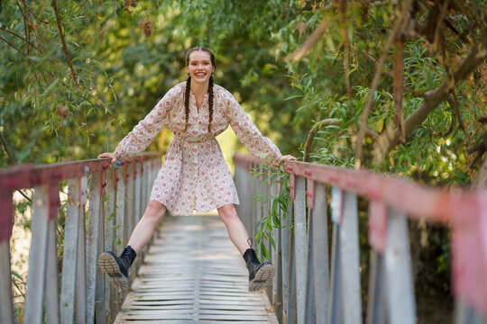 Happy woman enjoying on bridge in front of trees