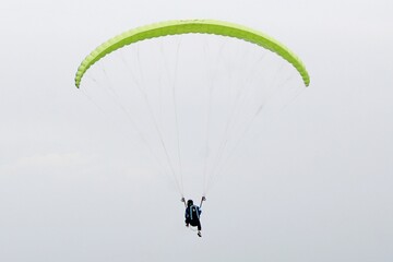 paragliding pilot flying in the blue sky with white clouds