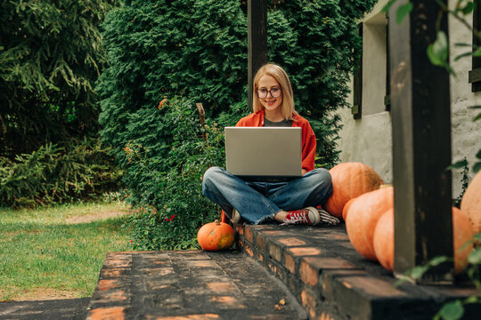 Freelance worker working on laptop sitting outside house