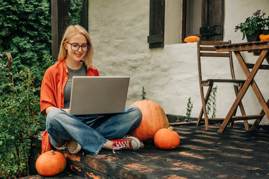 Smiling blond freelancer using laptop sitting on porch
