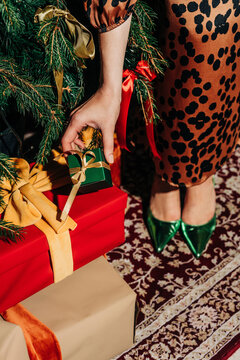 Fashionable woman holding small gift box near Christmas tree