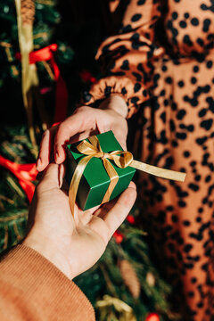 Hand of man giving gift to woman near Christmas tree