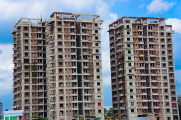 Naklejka premium Under construction residential twin tower buildings with concrete block or red bricks structure, Large multistorey building under construction with beautiful blue sky background 