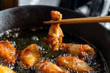 chicken wing fried until golden brown in bubbling hot vegetable oil, home cooking concept