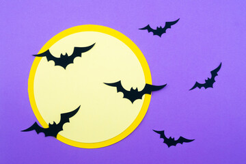Halloween decorations featuring bats flying around a large moon on a purple background