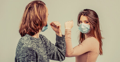 Friends in protective medical mask on his face greet their elbows in quarantine
