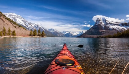 Kayaking in the spring by snow covered mountains on Lake McDonald in Glacier National Park 