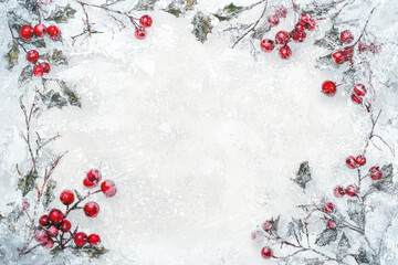 Christmas background with snow-covered pine branches, red berries, and free space in the center for text or design.