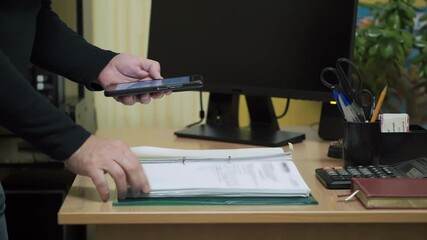 An employee takes photos of confidential documents in the office. A person steals important information in the concept of industrial espionage