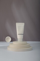 White Cosmetics tube mockup on concrete round stairs stand, grey background. Unbranded beauty container, no label template. Copy space