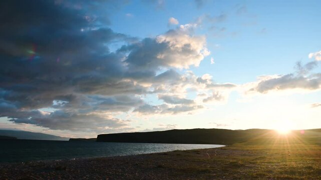 the sun rises from the horizon, clouds float rapidly over Lake Baikal