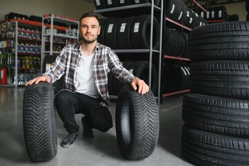 Fototapeta premium customer tire fitting in the car service, auto mechanic checks the tire and rubber tread for safety