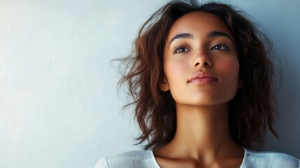Thoughtful young woman with curly hair, gazing upwards