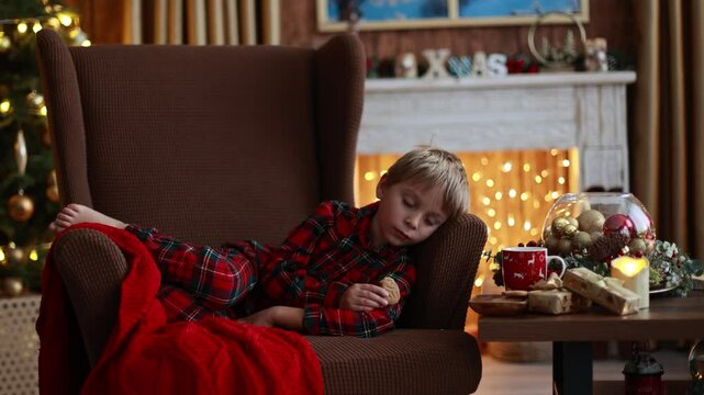 Sweet blond child, cute boy, playing with christmas toys on Christmas, beautifully decorated home for Christmas, cosy place
