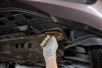 close up of hand with glove fixing bolt under car