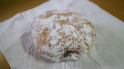 A close up photo of white sugar coated donut on the table.