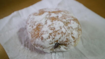 A close up photo of white sugar coated donut on the table.