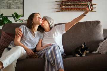Mother and daughter taking a selfie with dogs on the sofa
