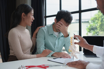A male doctor in a white uniform with a stethoscope sits and explains back problems to a patient. Health care and healthy living concept skeleton model Explaining to a stressed patient in the clinic.