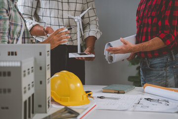 A skilled team of engineers work together in a meeting. Draft blueprints for condos, apartments and houses, wind turbines, real estate investment construction, agreements, agents, leases.