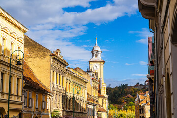 Brașov's historic street with clock tower. A charming street in Brașov showcases colorful...