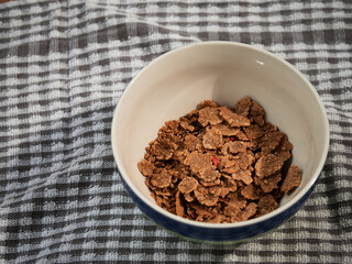 Pouring breakfast cereal flakes into a bowl 