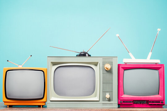 Retro TVs set on table front mint blue background. Vintage old style filtered photo