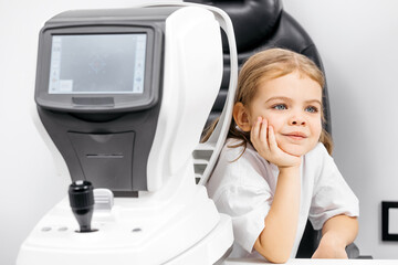 A child being examined with a slit lamp—a device with a microscope and focused light to assess...