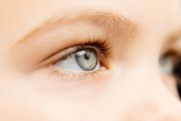 Obraz premium Close-up of a girl's eyes, showcasing the beauty of her expressive gaze. This macro shot highlights the depth of her look, perfect for illustrating themes of beauty and childhood aesthetics.
