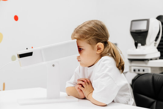 A girl participates in an engaging vision enhancement therapy using cutting-edge equipment. This laser treatment aids in restoring and developing visual skills.