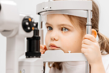 Examination of a little girl's eyes in an ophthalmology clinic. A laser beam shines into the...